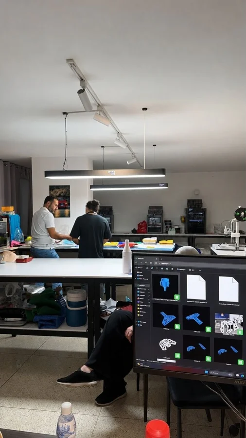 LayerLab workspace in Venezuela with Bambu printers producing relief items, a screen showing sliced orthosis models
